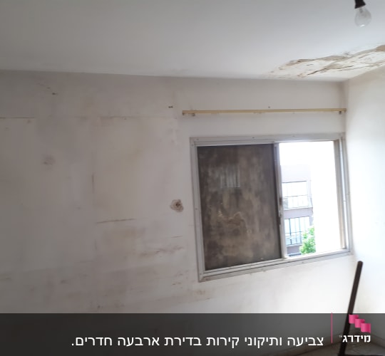 קיר מתקלף עם סימני רטיבות ליד חלון